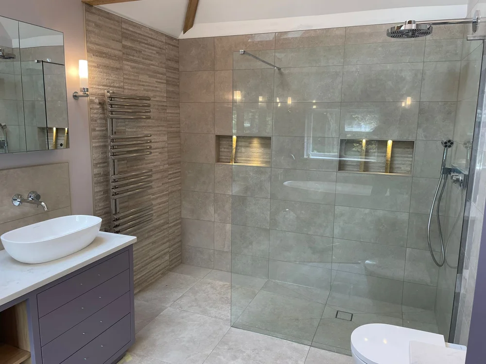 Modern bathroom with glass shower, wall-mounted showerhead, sink on vanity, towel radiator, and toilet.