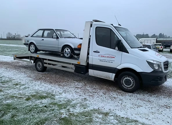 Broken down ford escort mkIII on the back of a pick up lorry.