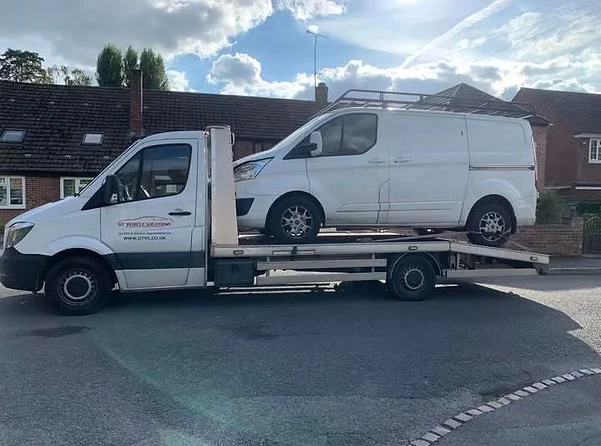 Broken down Ford Transit van on the back of a lorry.