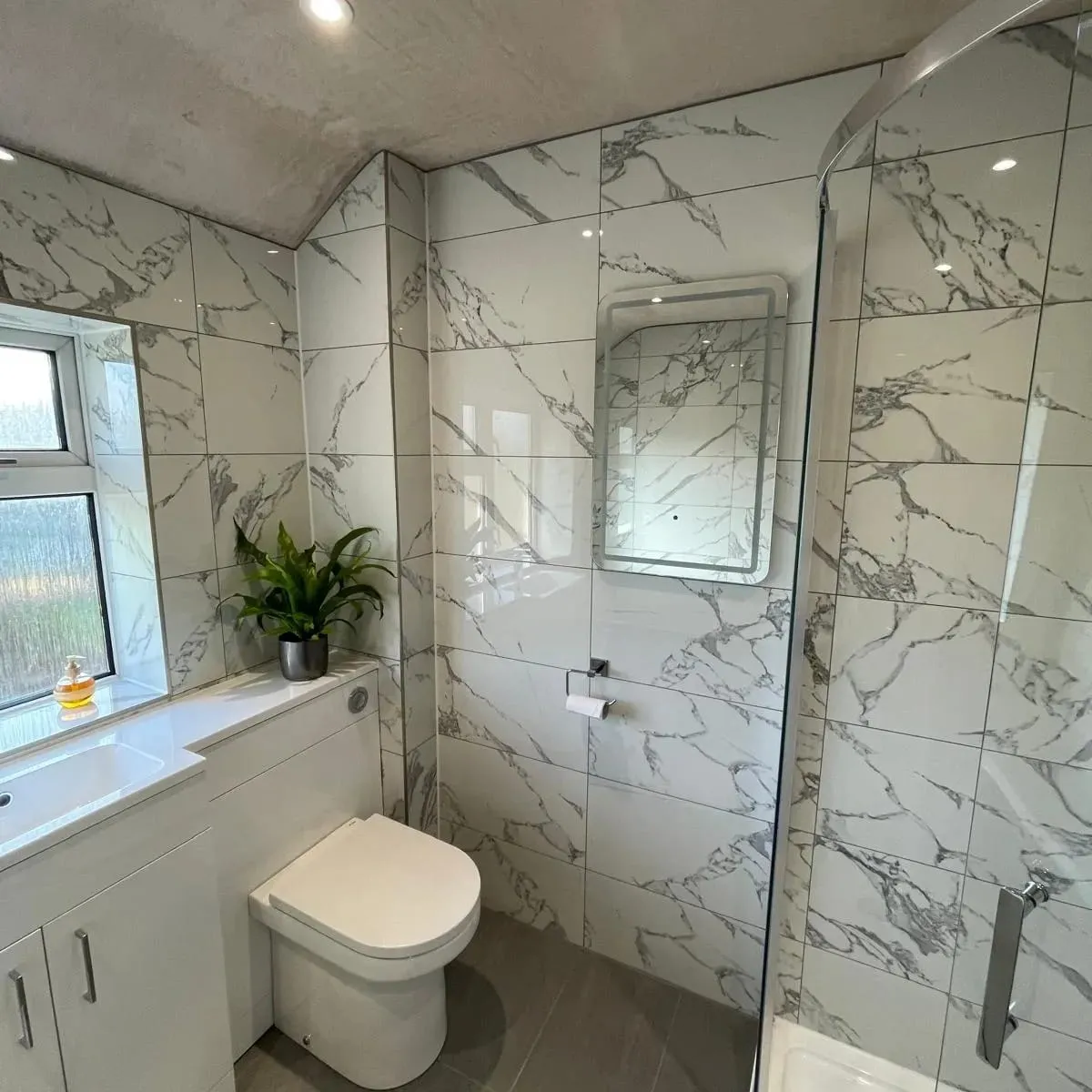 a white toilet sitting next to a window in a bathroom