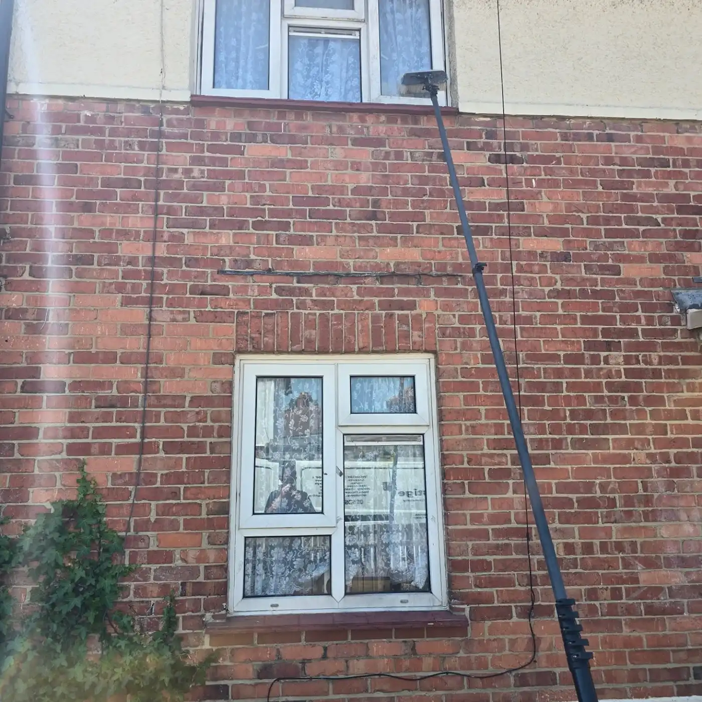 Pressure washing a top floor window.