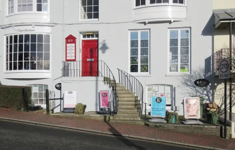 A white building with a red door and stairs.