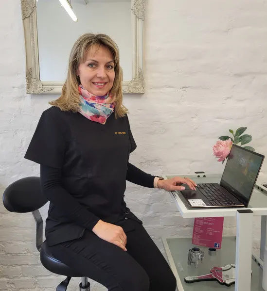 Dr Anita sitting at a desk with a laptop.