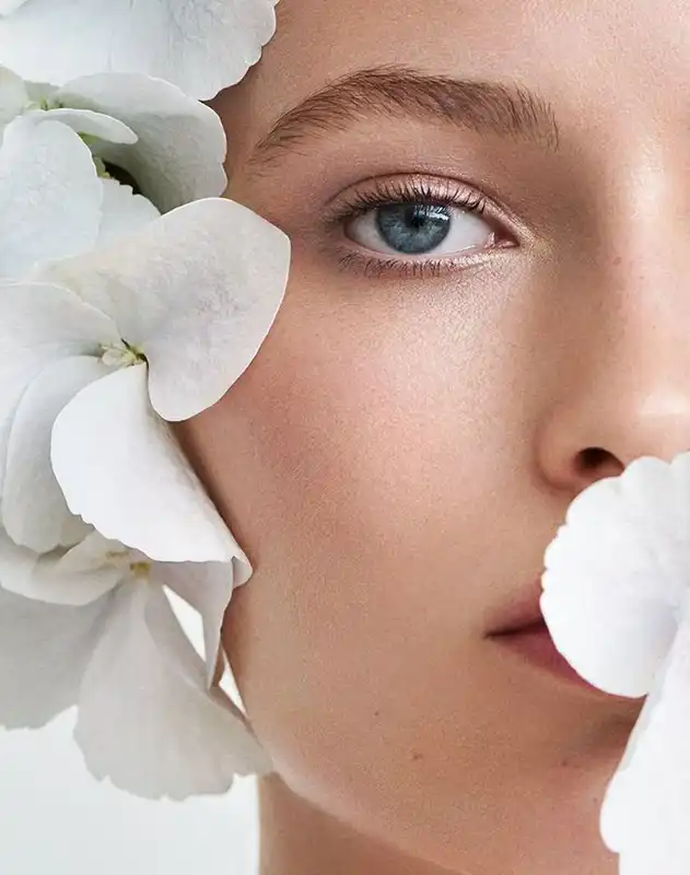 A woman with blue eyes and white orchids in her hair.