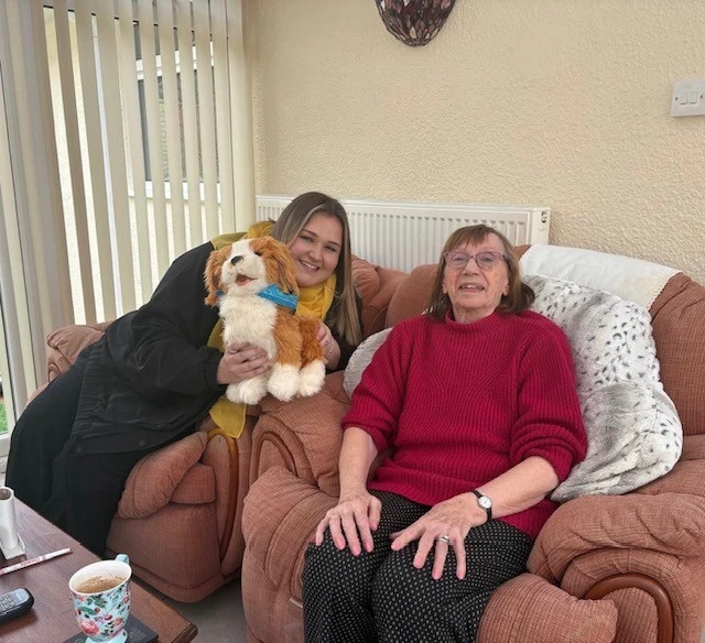two women sitting on the sofa with a dog