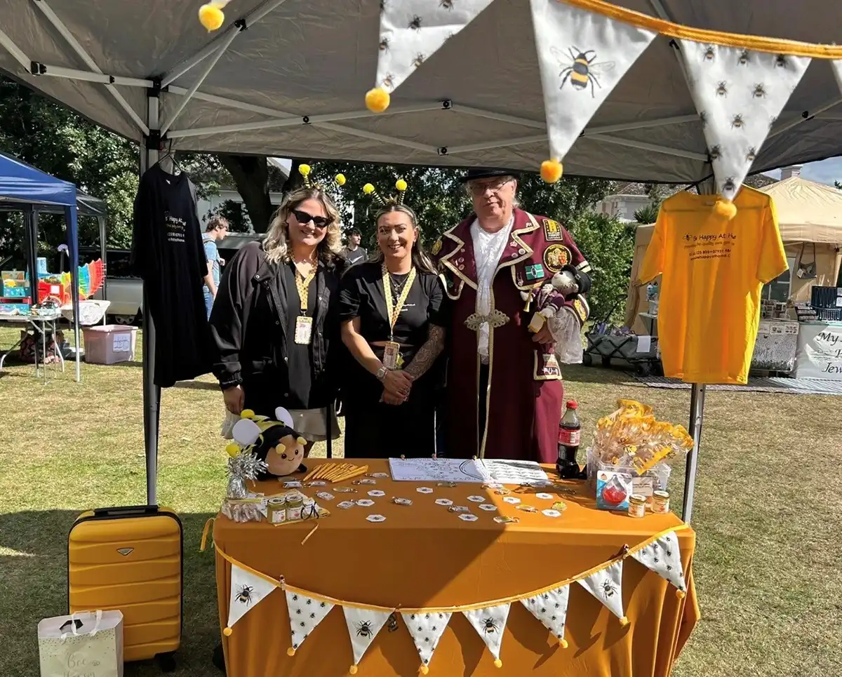 three people at a summer fayre, one is the mayor