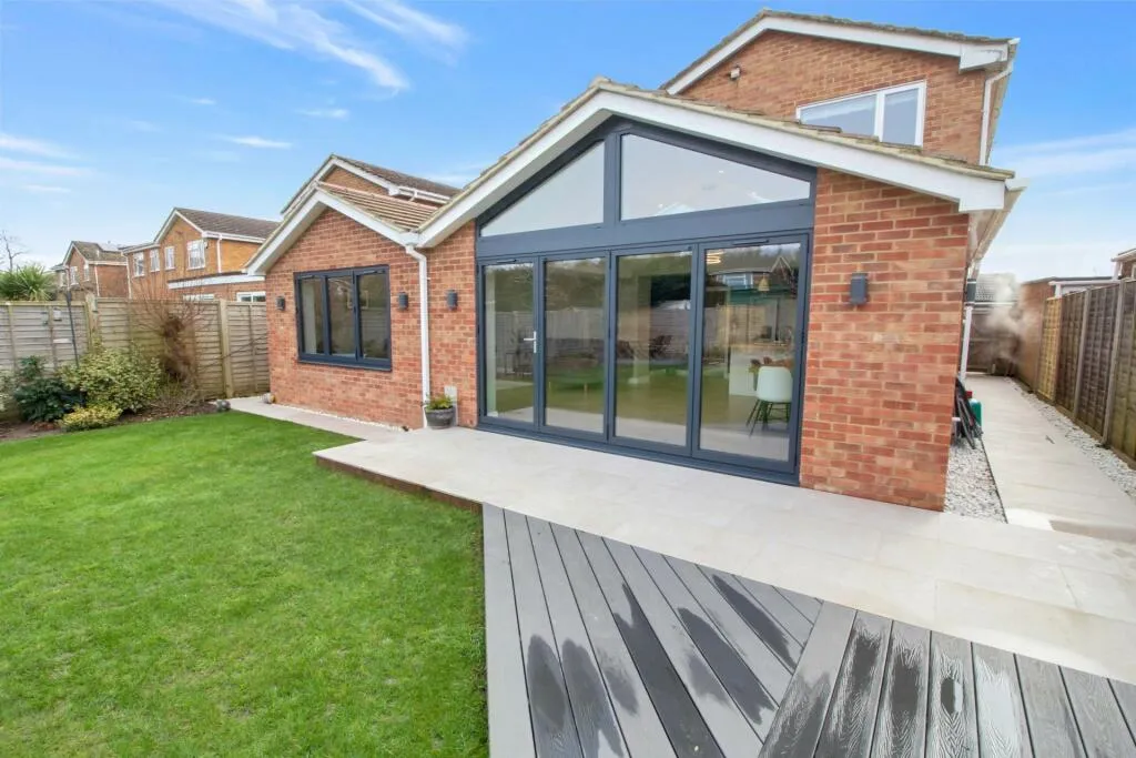 A backyard with a wooden deck and a brick building.