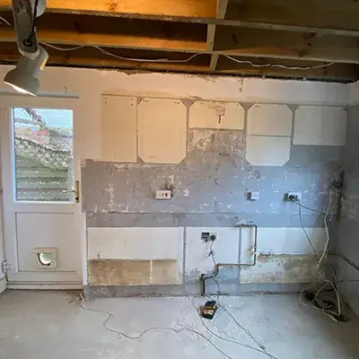 An unfinished kitchen with white cabinets and a ceiling fan.