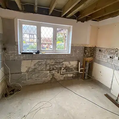 An unfinished room with a window and a sink.