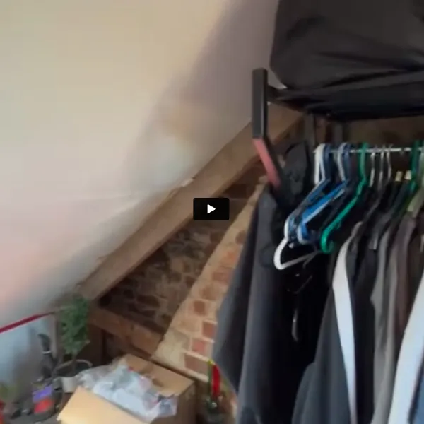 A closet filled with clothes next to a brick wall.
