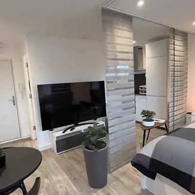 A bed room with a neatly made bed and a flat screen tv.