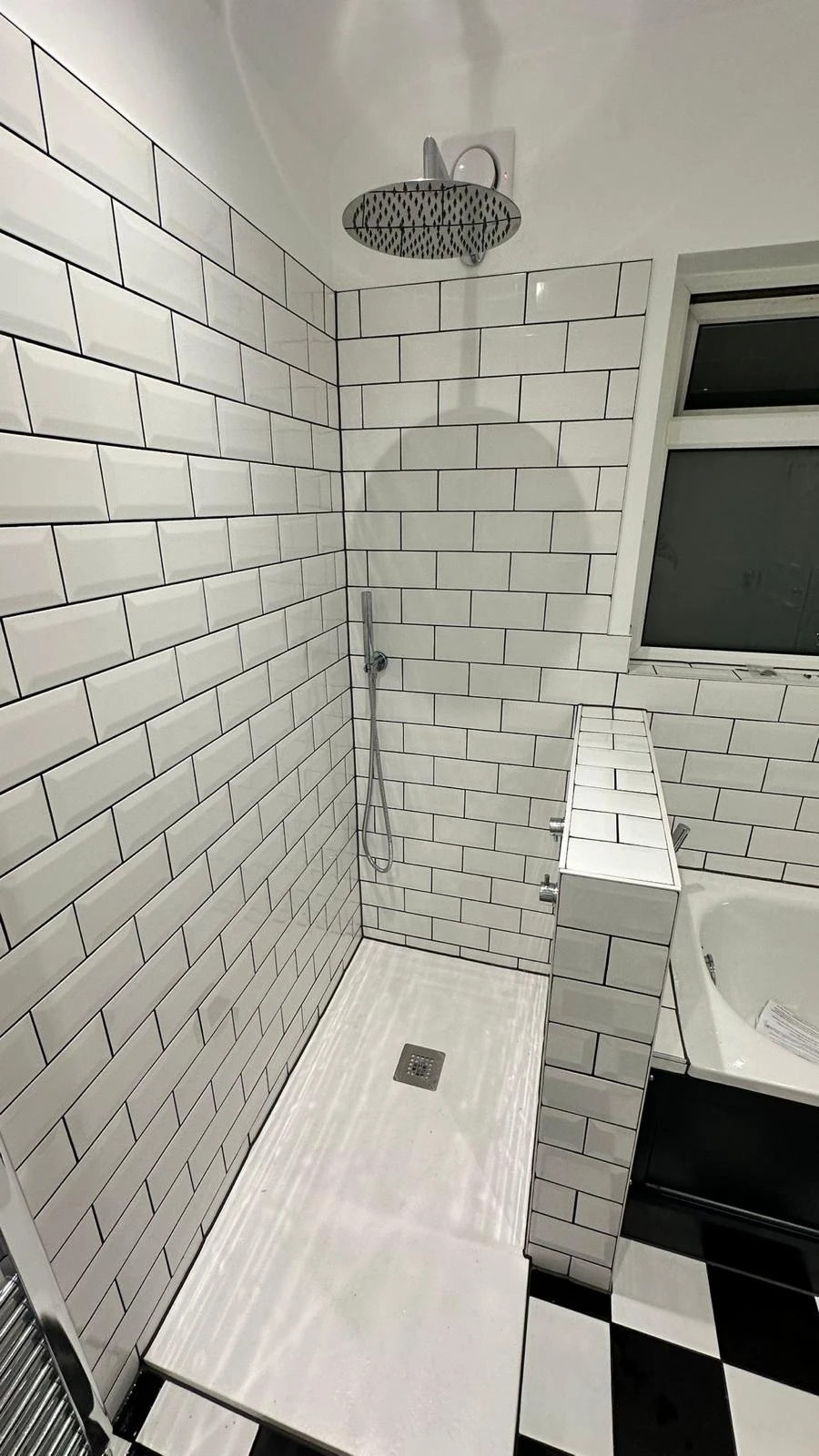 Modern bathroom shower area with white subway tiles, a rainfall showerhead, and a sleek, minimalist design.