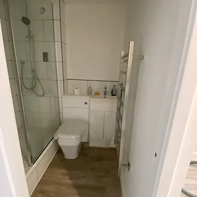 A bathroom with a toilet, shower, and sink.