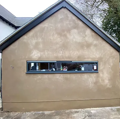 A small building with a window and a cat sitting in the window.