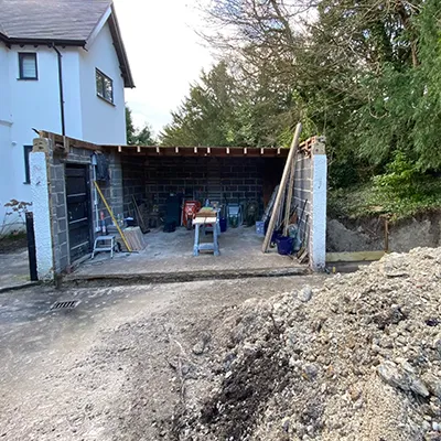 A house is being built with a large pile of dirt in front of it.