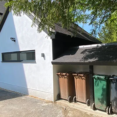 A row of trash cans sitting next to a white building.