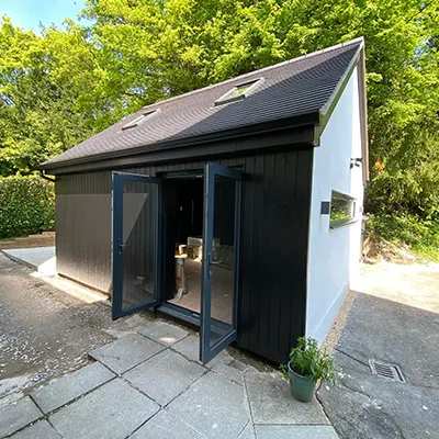 A small black and white building with a door open.