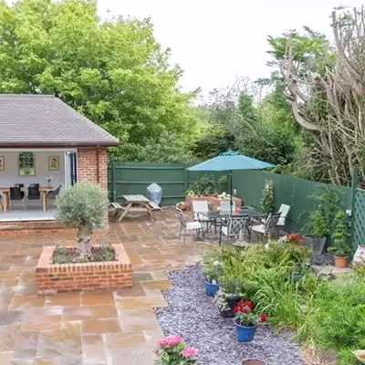 A patio with a table, chairs and a potted plant.