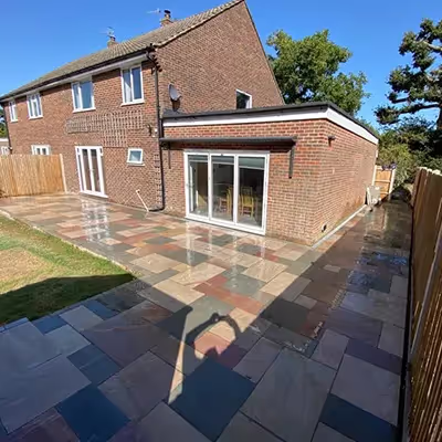 A backyard with a brick patio and a wooden fence.