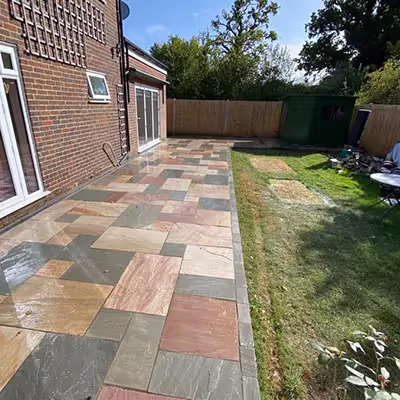 A backyard with a large brick patio and grass.