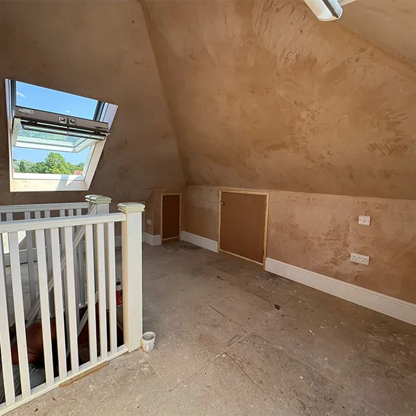 An empty room with a white railing and a skylight.