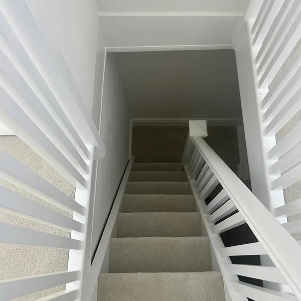 A white staircase with a black and white handrail.