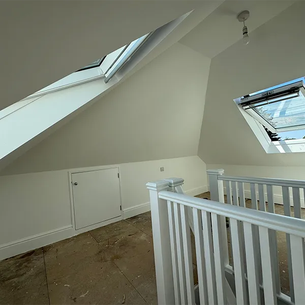 A room with a white railing and a skylight.