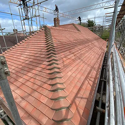 A man on a scaffold working on a roof.