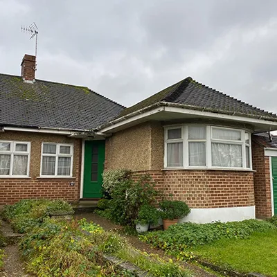 A brick house with a green door and windows.
