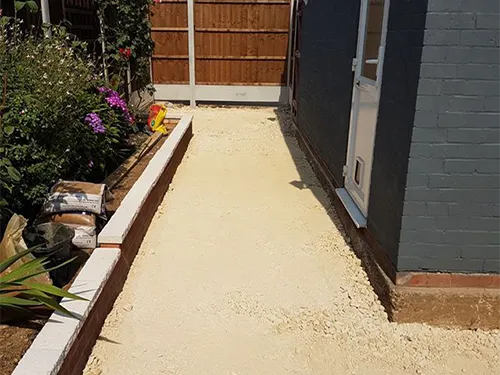 a backyard with a concrete walkway and a fence