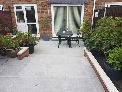 a patio with a table and chairs surrounded by plants