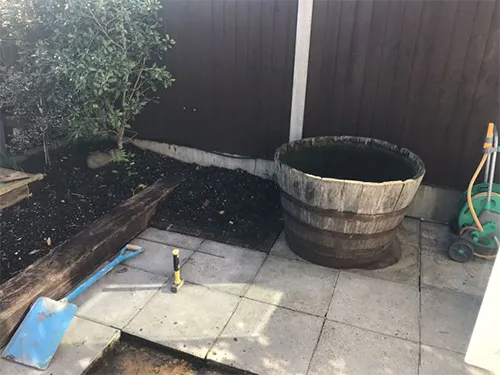 a garden with a wooden barrel and a garden hose