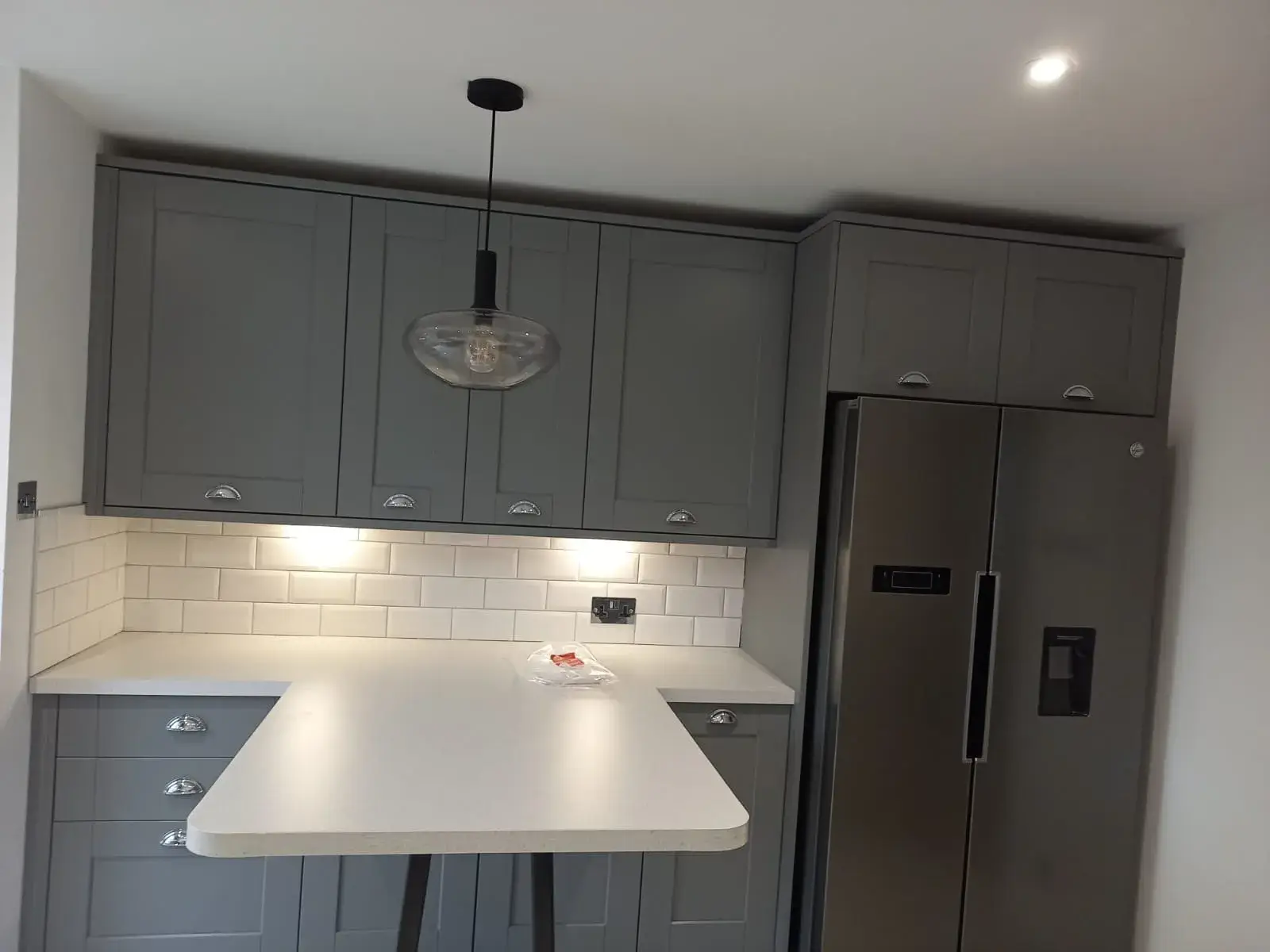 a kitchen with grey cabinets and a white counter top