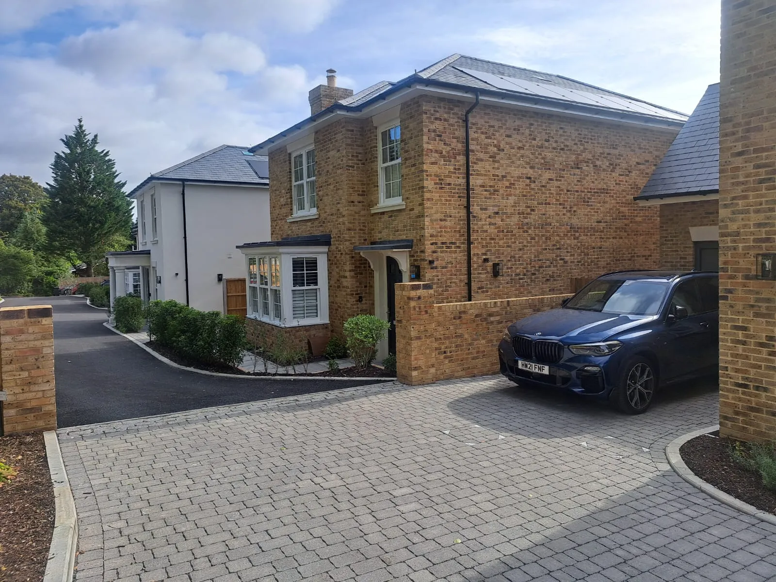 brick driveway with a car parked in front of a house