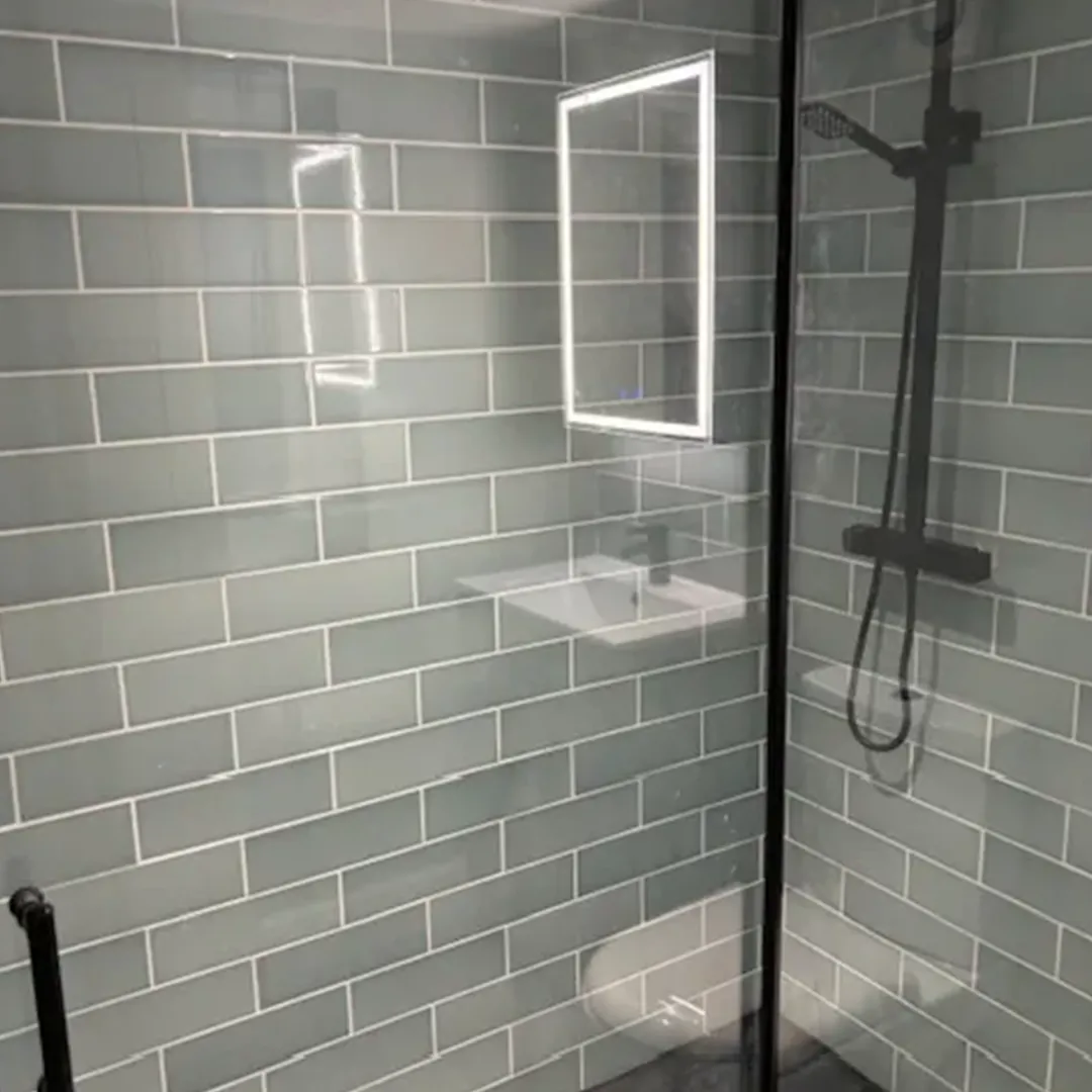 A bathroom with a glass shower door and a sink.