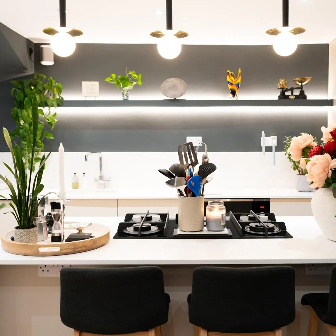 A kitchen with a stove top oven sitting next to a vase of flowers.