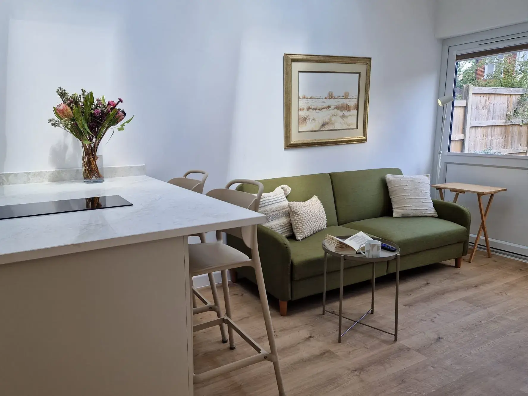 A green couch sitting in a living room next to a kitchen.