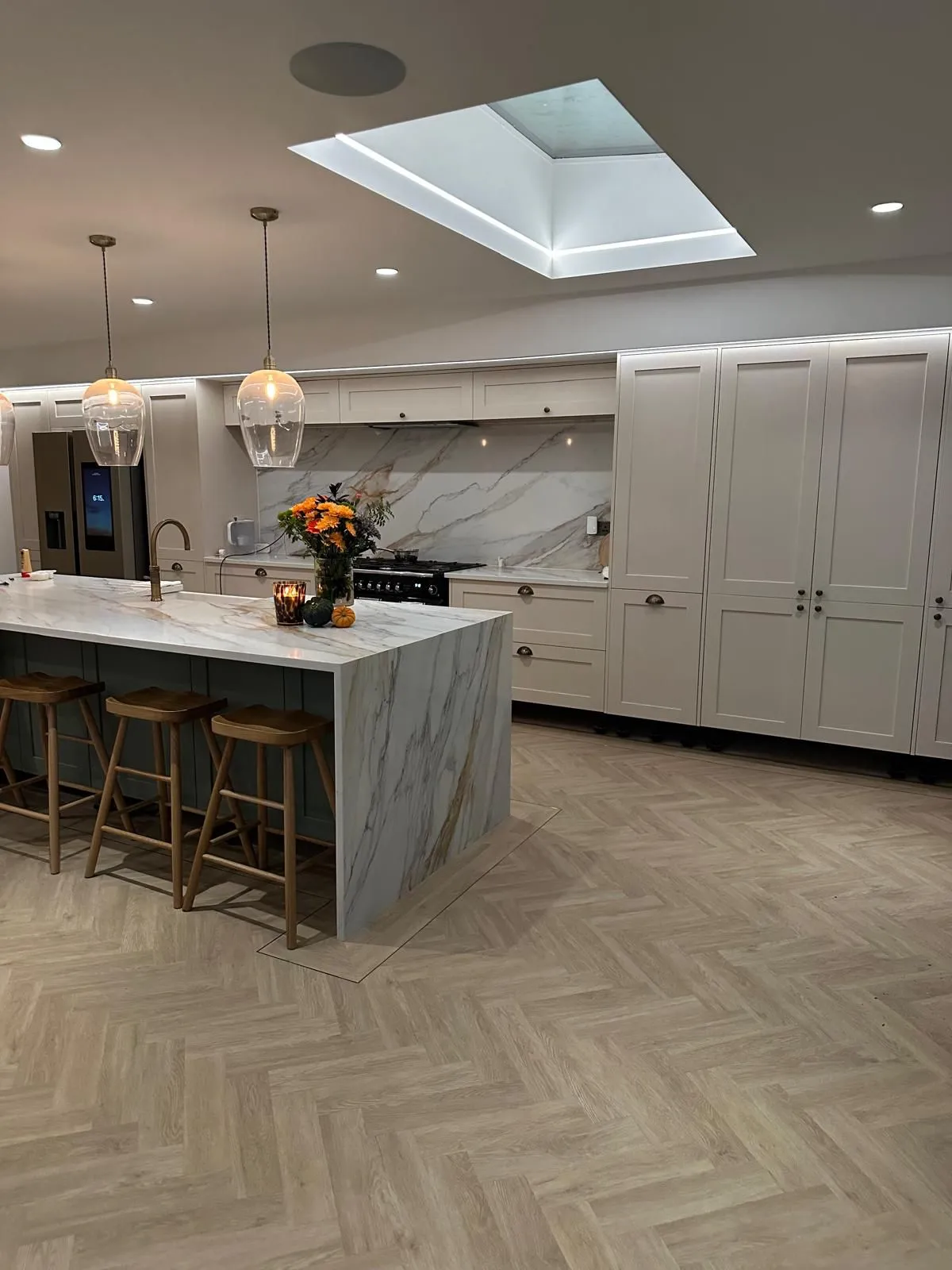 A large kitchen with a center island and marble counter tops.